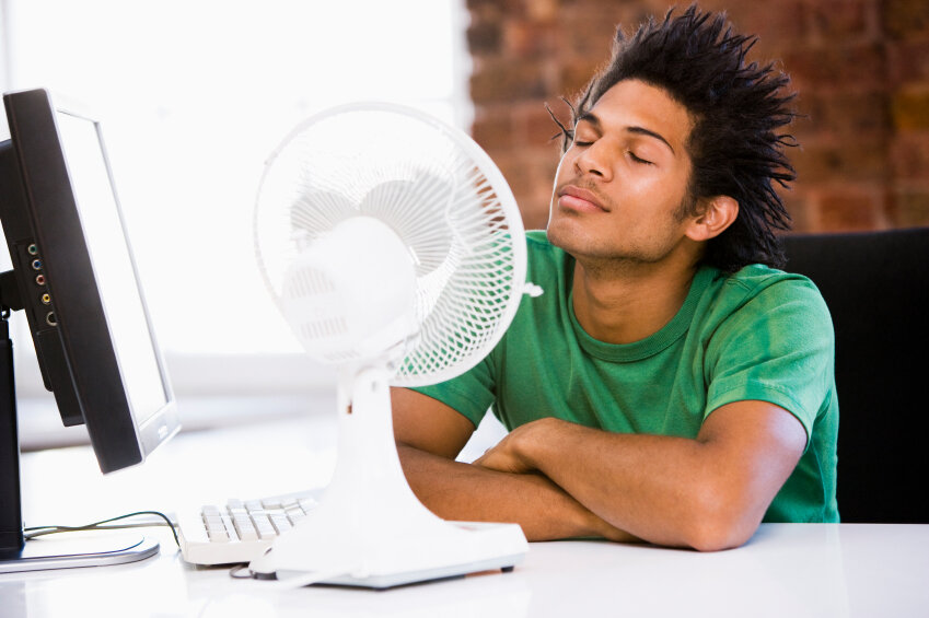Businessman in office with computer and fan cooling off